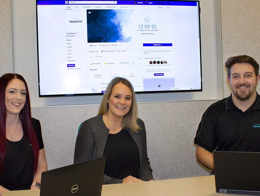 The TasWater social media team at their desks with the utility’s Facebook page on screen