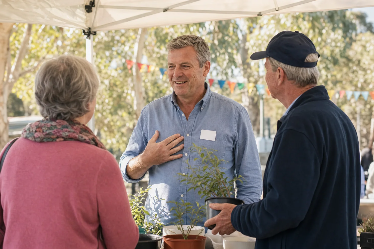 A councillor talking with residents at a community market stall