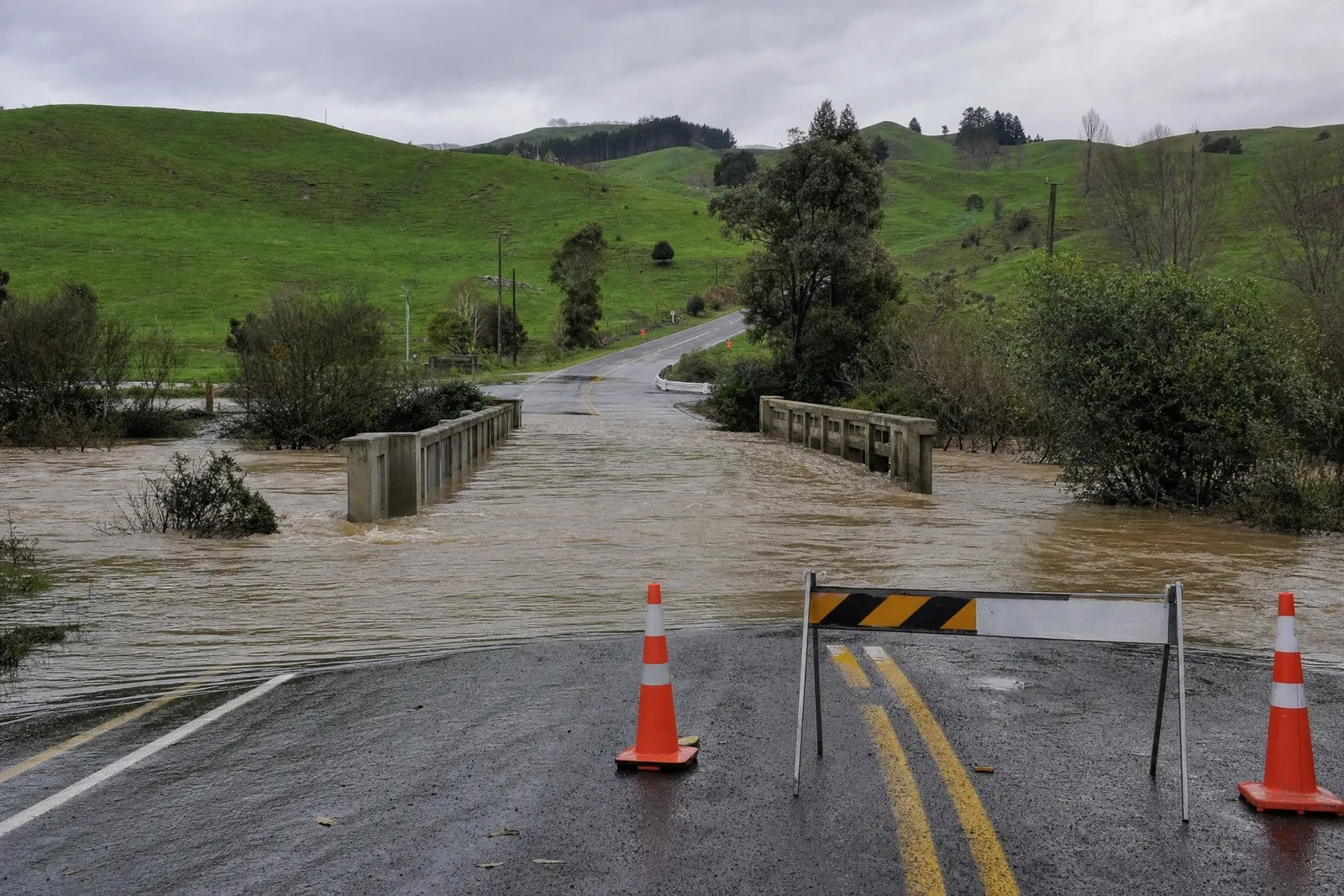 A flooded road closed at a bridge crossing