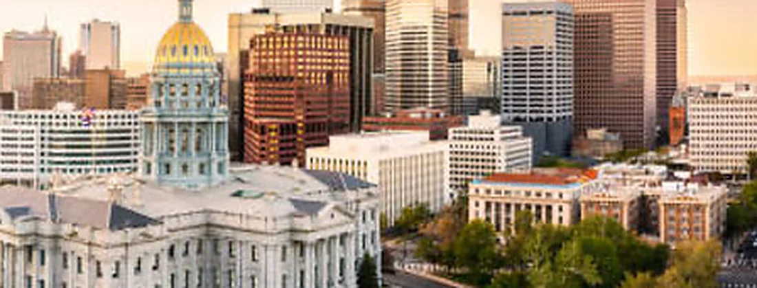 The gold dome of the Colorado State Capitol with the Denver skyline behind it